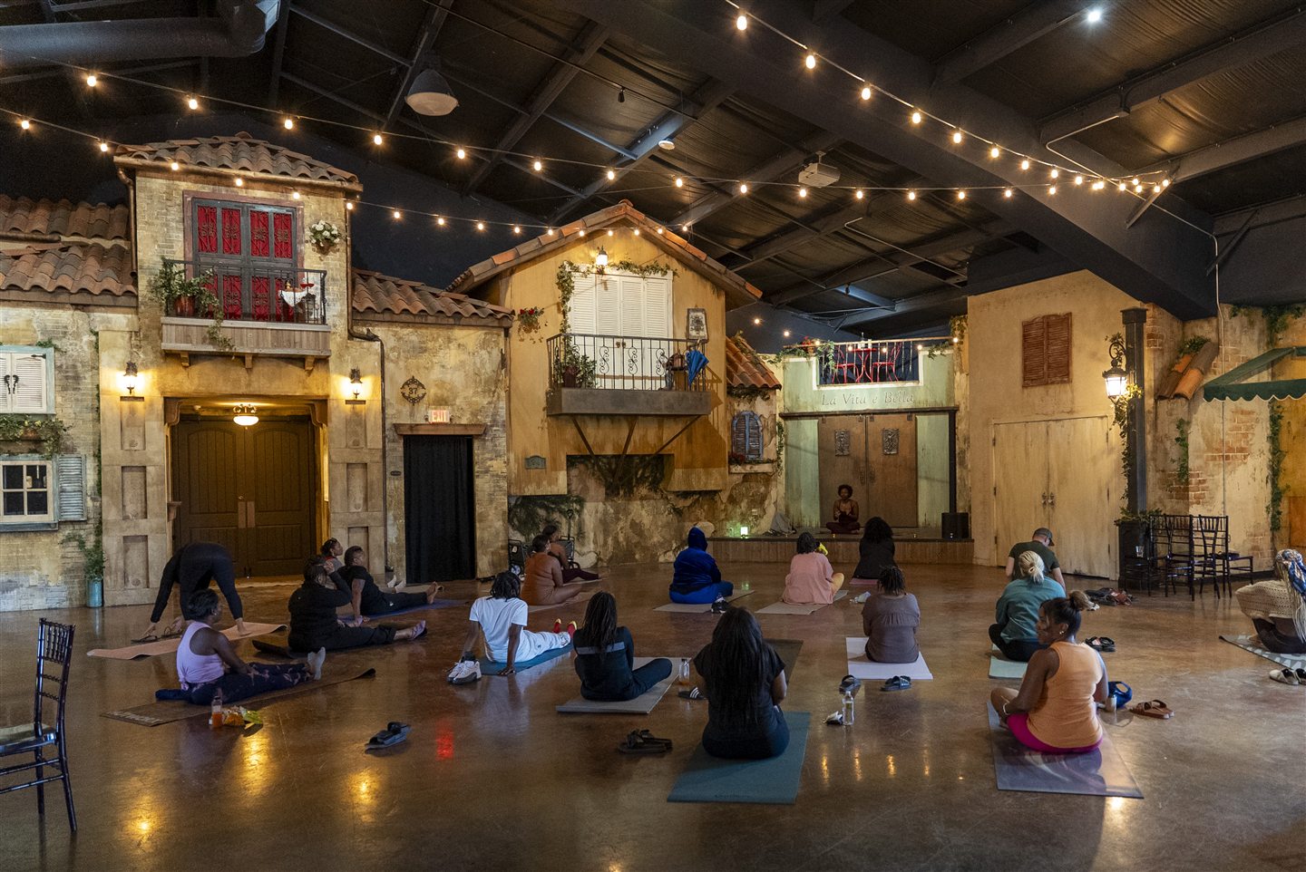 Gathering for guided movement beneath the string lights.